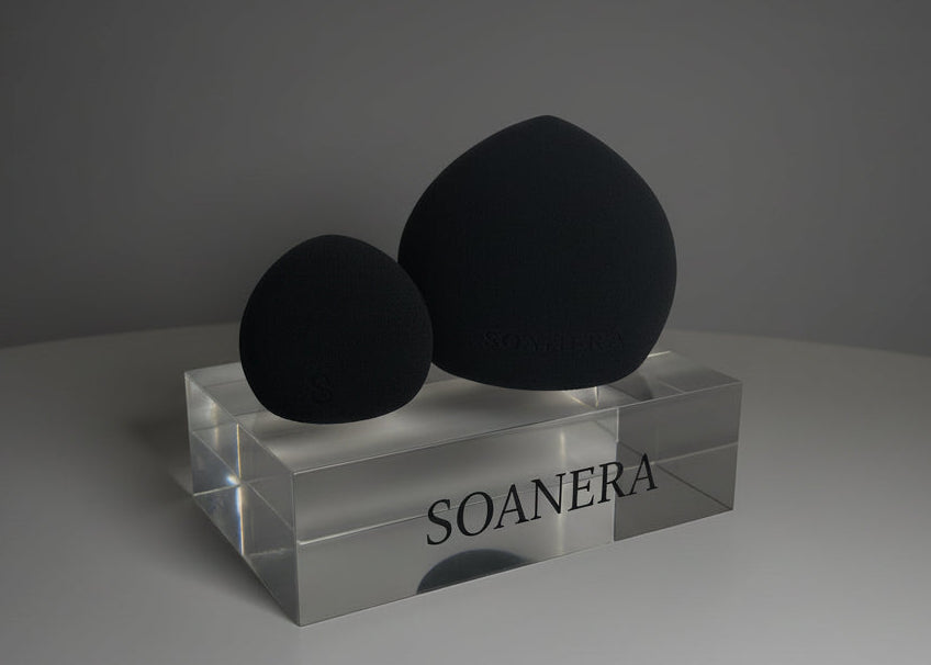 Two black beauty sponges on a clear stand with 'SOANERA' branding against a gray background.