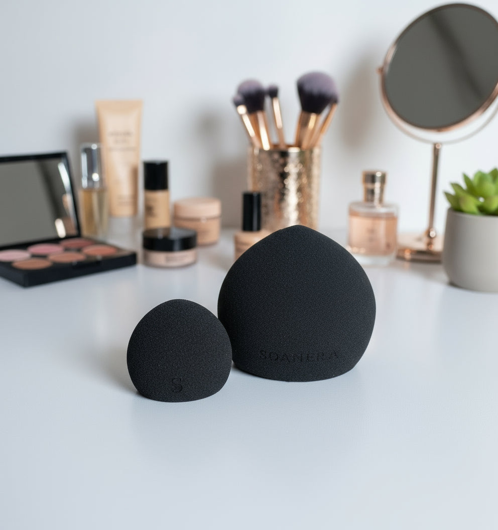 Black makeup sponges on a white surface with cosmetic products in the background